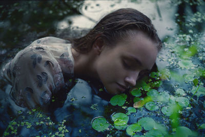 A woman in a white dress on the surface of a swamp water in the forest