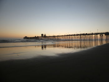 Pier on sea against clear sky during sunset