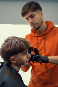 Barber trimming teenager male haircut