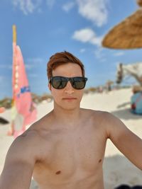 Portrait of shirtless man wearing sunglasses at beach