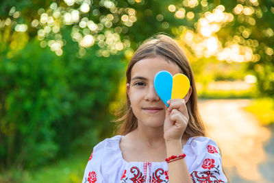 Girl covering eye with painted heart shape