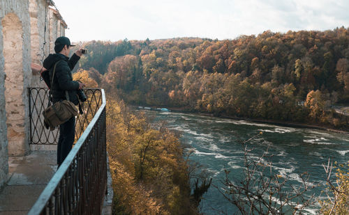 Man standing on riverbank against sky