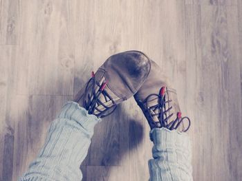 Low section of woman wearing shoes on hardwood floor