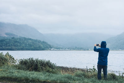 Rear view of man standing by lake