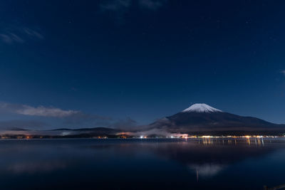 Scenic view of lake and mountains against sky at night