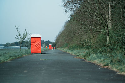 Diminishing perspective of empty road amidst trees against clear sky