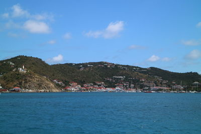 Scenic view of sea by townscape against sky