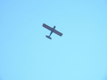 Low angle view of airplane against clear blue sky