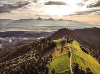 Drone capture of a little white church on top of a green hill surrounded by mountains in slovenia 