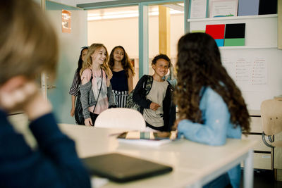 Smiling male and female students entering in classroom