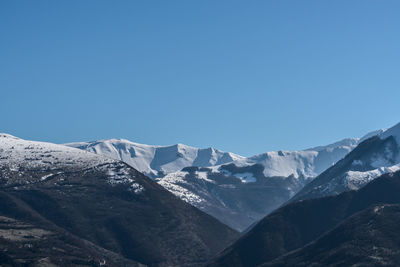 Scenic view of snowcapped mountains against clear blue sky