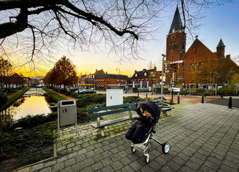 Man on street by buildings against sky during sunset