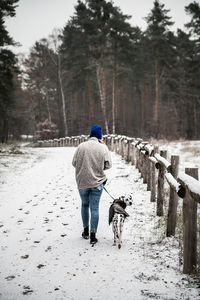 Rear view of man with dog running in lake