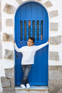 Little kid in front of a blue and white door