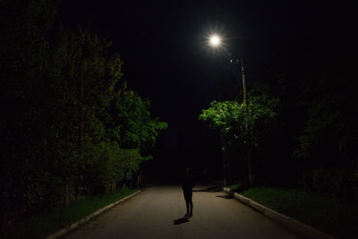 Man standing on illuminated tree against sky at night