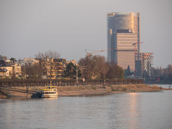 Scenic view of river by buildings against clear sky