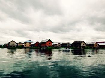 Houses by lake against sky