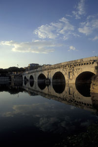 Arch bridge over river against sky in city