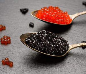 Grainy caviar of paddlefish fish and red chum salmon caviar in a spoon, black background, close up