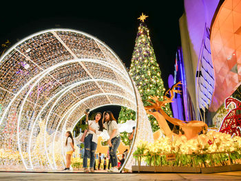 People standing by illuminated building at night