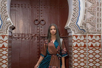 Portrait of woman standing against closed door