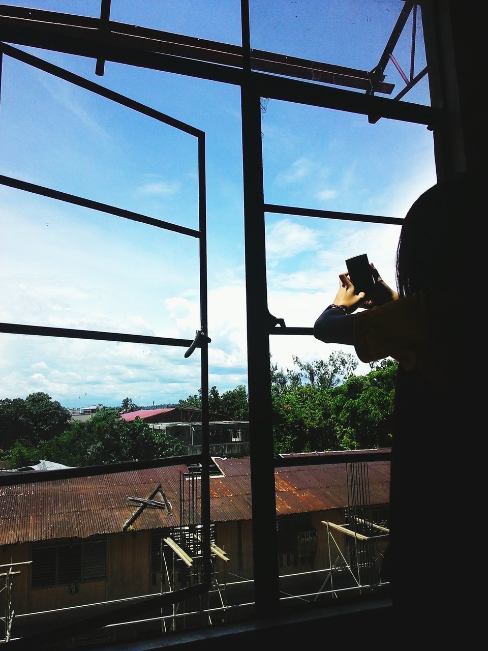 sky, architecture, built structure, indoors, glass - material, transparent, window, building exterior, cloud - sky, cloud, transportation, city, men, low angle view, silhouette, looking through window, lifestyles, day