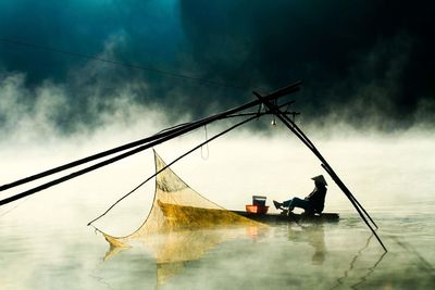 Boats in sea against cloudy sky