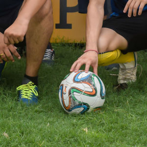 Low section of people playing soccer on field