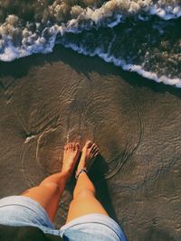 Low section of woman standing at beach