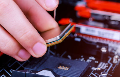 Cropped image of technician installing computer chip in circuit board