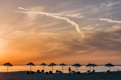 Man standing on beach against sky during sunset