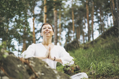 Young smiling woman practice yoga outdoors in forest. new normal social distance. physical and 