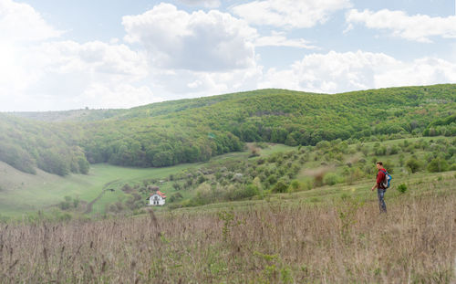 Adult man walks on the hill above a small isolated settlement in