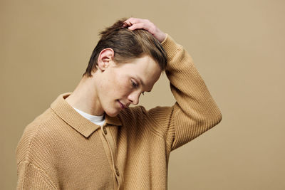 Side view of young man standing against wall