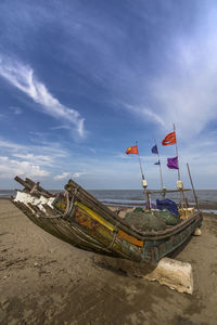 Boat moored on beach against sky