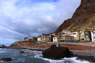 Buildings by sea against sky