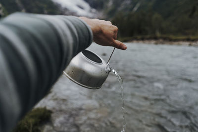 Cropped hand pouring water in lake