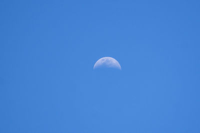 Low angle view of moon against blue sky at night