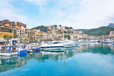 Boats moored in harbor by buildings in city against sky