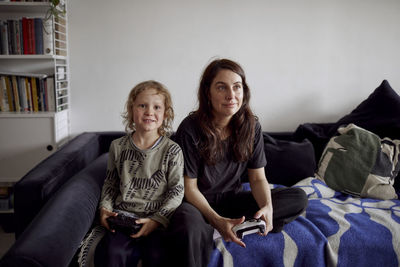 Mother and son playing video games on sofa