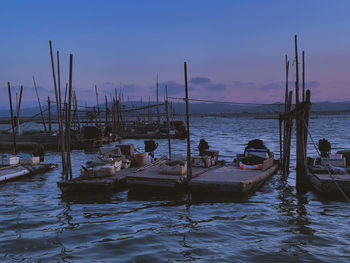 Sailboats moored in sea against sky during sunset