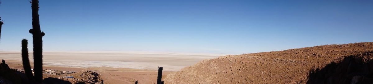 Panoramic view of arid landscape against clear blue sky