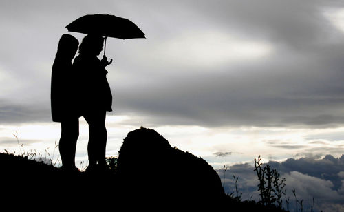 Low angle view of silhouette woman standing against sky