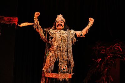 Rear view of woman with arms raised standing at home