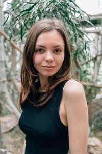 Portrait of young woman standing against plants