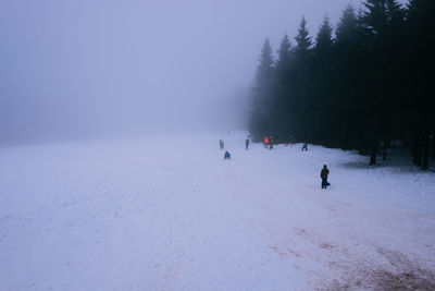 People on snow covered landscape against sky