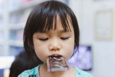 Cute girl carrying plastic in mouth at home