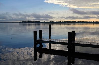 Pier on lake against sky during sunset