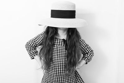 Low section of woman wearing hat standing against white background