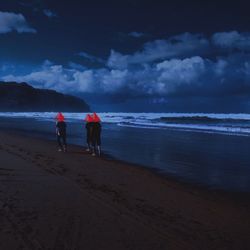 Digital composite image of friends with red masks walking at shore
